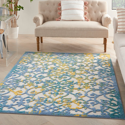 Rectangular area rug with blue turquoise and yellow scroll pattern on a light background in a cozy living room with a beige tufted sofa.