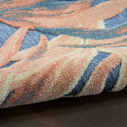 Soft peach, blue and cream abstract rug with plush thick pile, folded edge on dark wood floor.