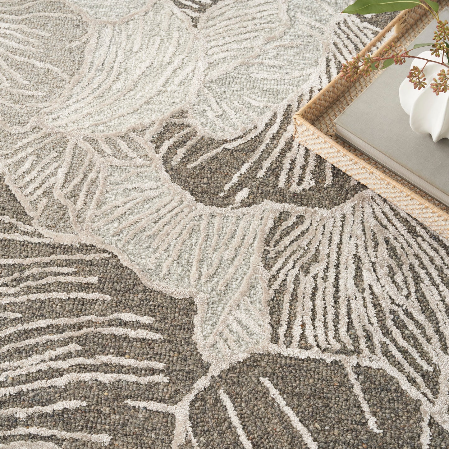 Neutral textured area rug with cream palm-leaf pattern on gray.