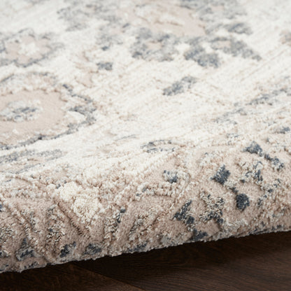 Beige and gray floral-patterned area rug with plush pile on dark wood floor.