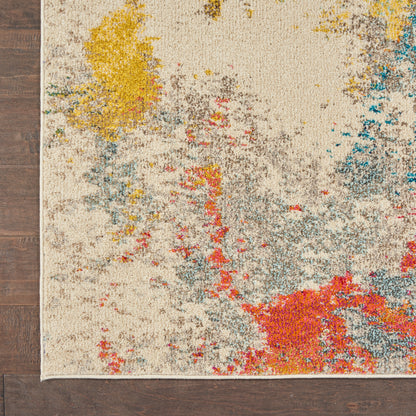 Cream rug with abstract multicolor splashes (yellow, red, blue, gray) and fringed edge on dark wood floor.