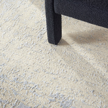 Black textured square sofa leg on beige, gray abstract-pattern rug.