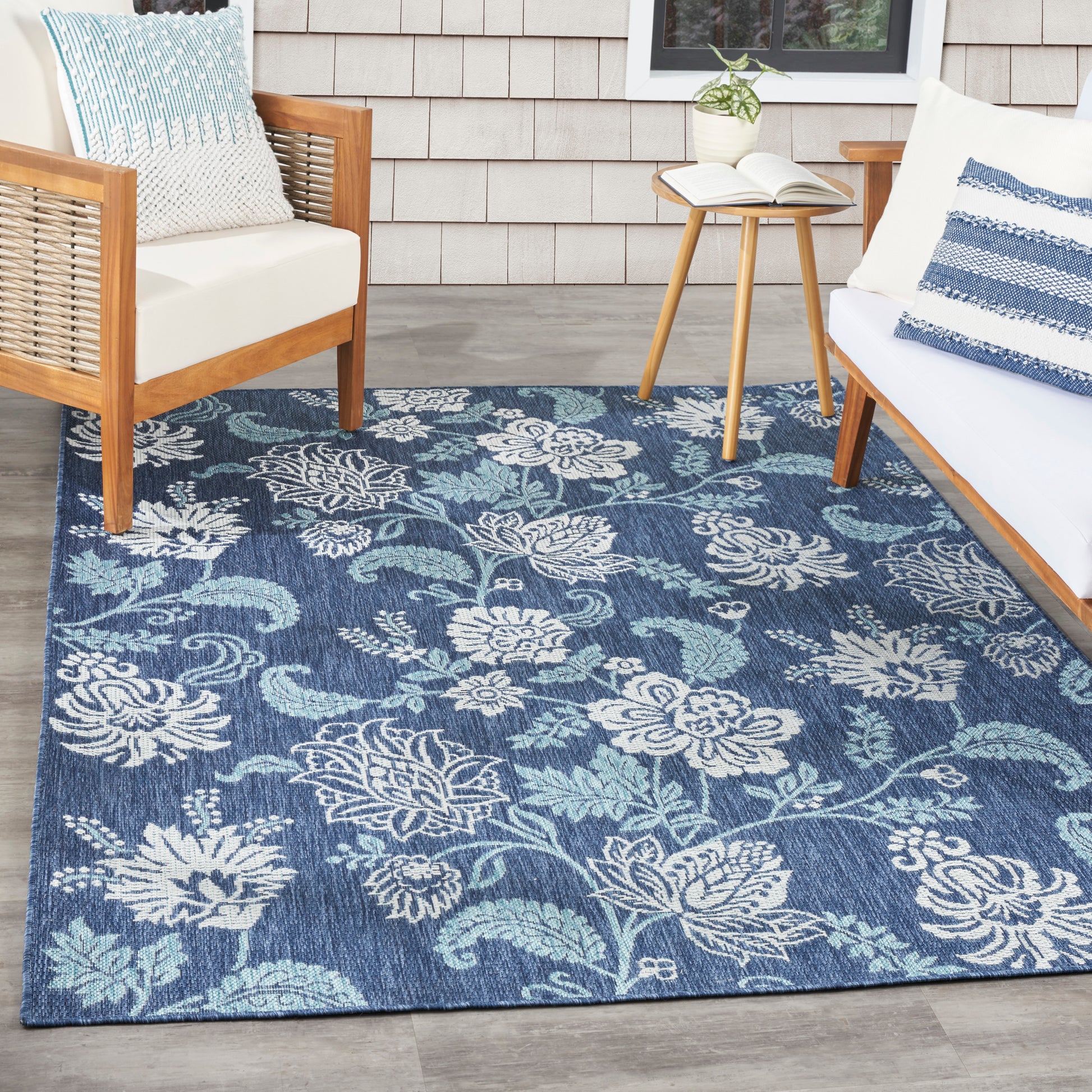 Blue floral woven area rug with white and teal blossoms; ideal for outdoor porch seating.