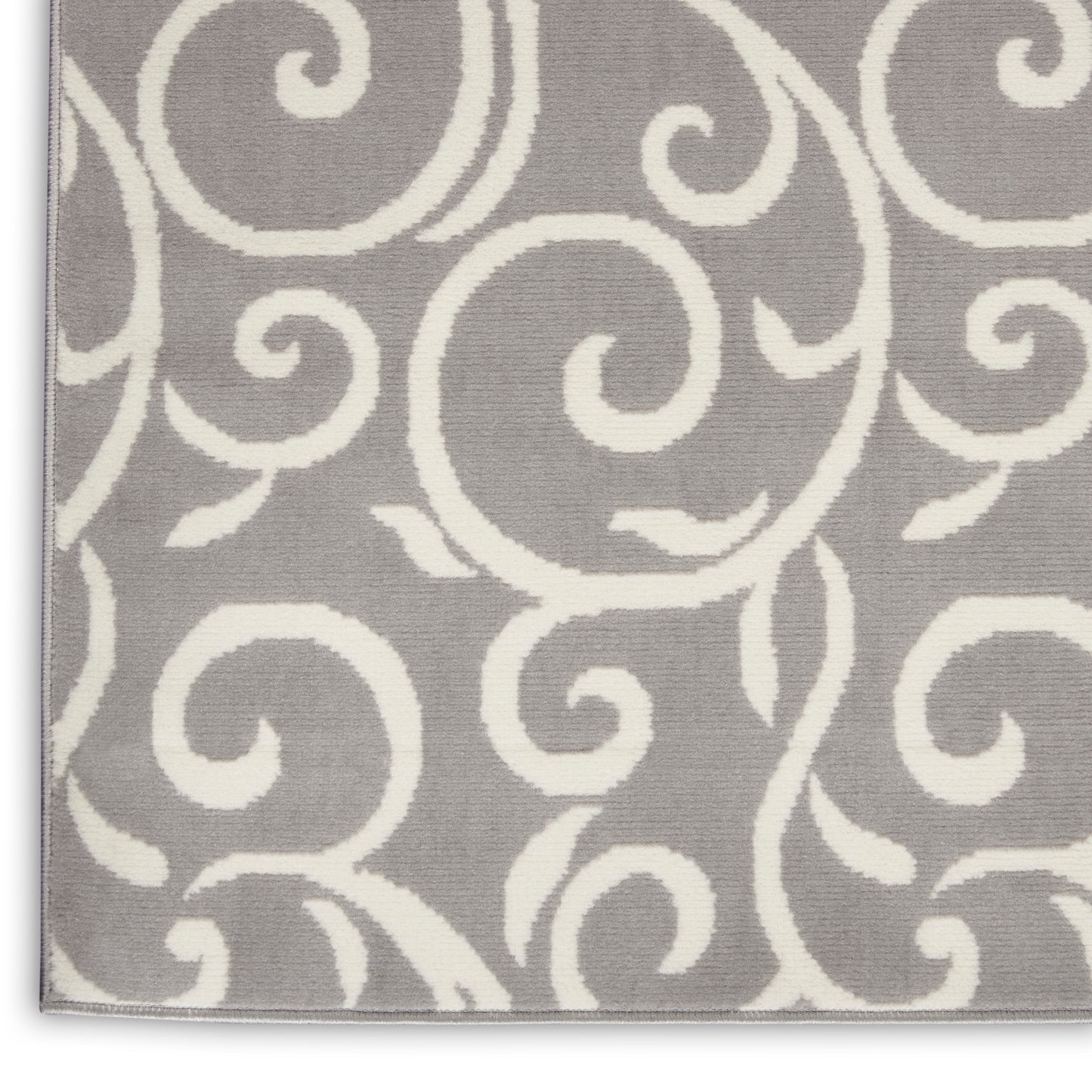 Gray rug with an allover white swirling scroll pattern; soft decorative rug.