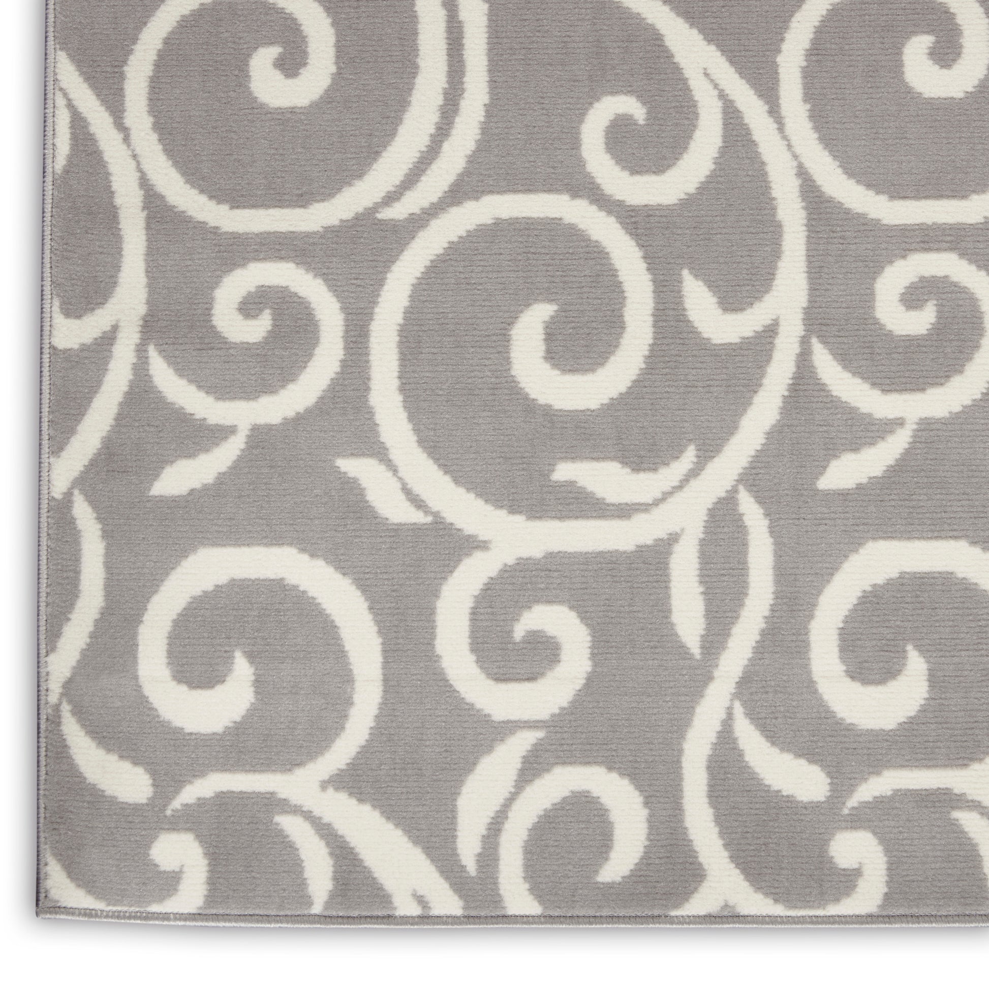 Gray rug with an allover white swirling scroll pattern; soft decorative rug.