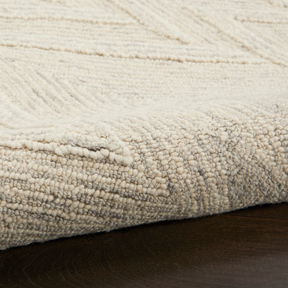 Beige textured area rug with boucle pile and subtle geometric pattern on dark wood floor.