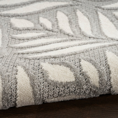 Grey and ivory patterned rug with leaf motif, plush pile on dark wood floor.