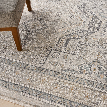 Neutral gray-beige Oriental-style area rug with intricate geometric borders and light blue accents; chair leg visible.