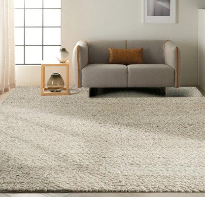 Light grey 2-seat sofa with orange piping and brown cushion, on a cream shag rug beside a wooden side table with vases.