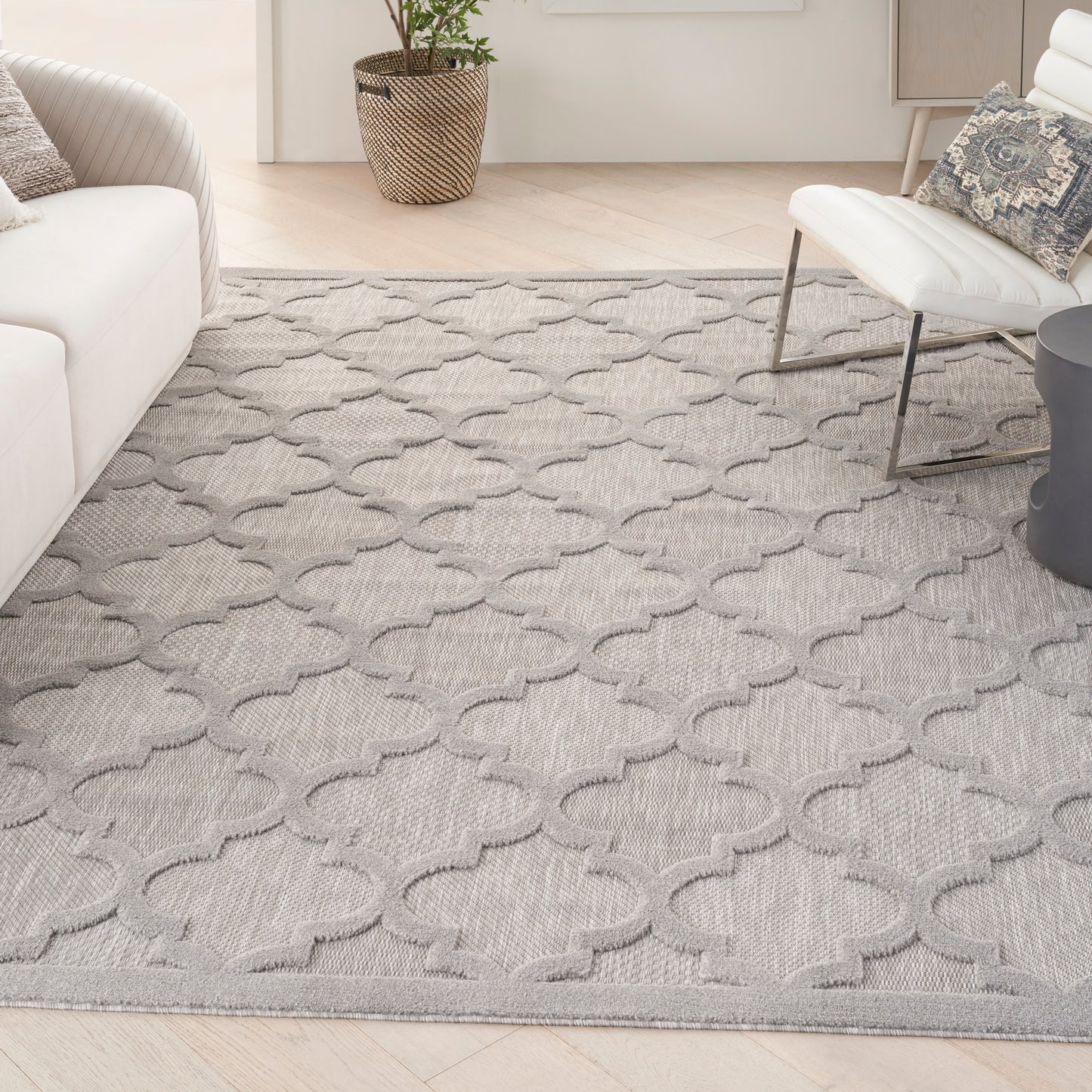 Gray area rug with interlocking quatrefoil/trellis pattern in a modern living room.