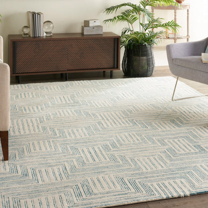 Light blue and cream geometric area rug with chevron blocks in a contemporary living room, paired with a wooden sideboard and lush potted plant.