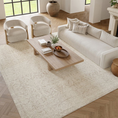 Neutral living room with cream sofa, rounded wood-arm chairs, low wooden coffee table, beige rug.