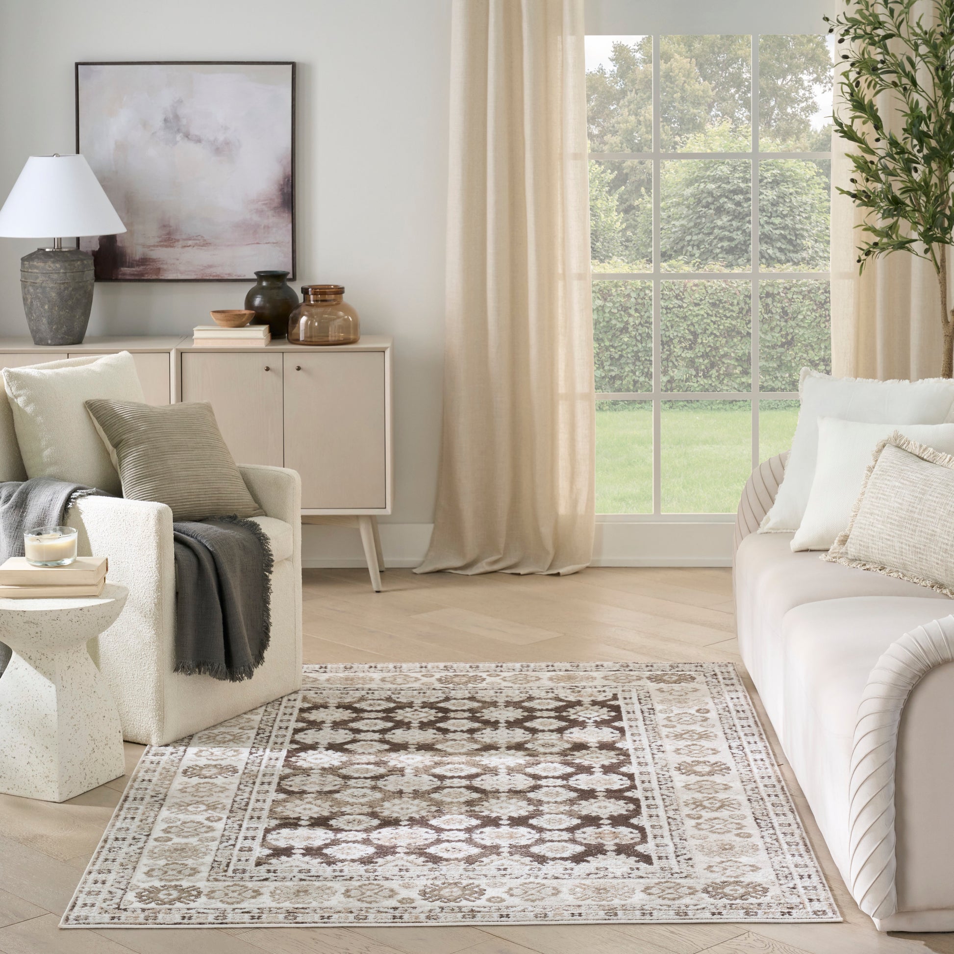 Neutral traditional-pattern area rug in beige and brown tones laid on a light wood floor in a bright living room.
