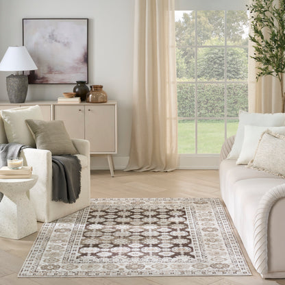 Neutral traditional-pattern area rug in beige and brown tones laid on a light wood floor in a bright living room.