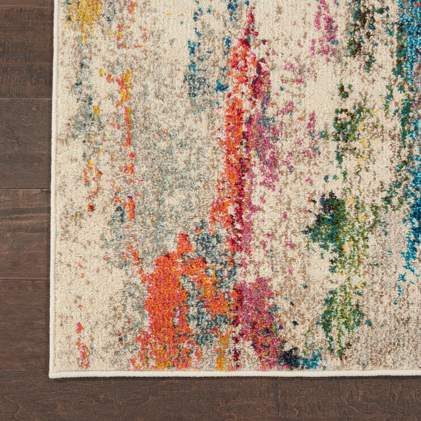 Beige abstract area rug with colorful splashes in orange, pink, blue, green on cream background, on dark wood floor.