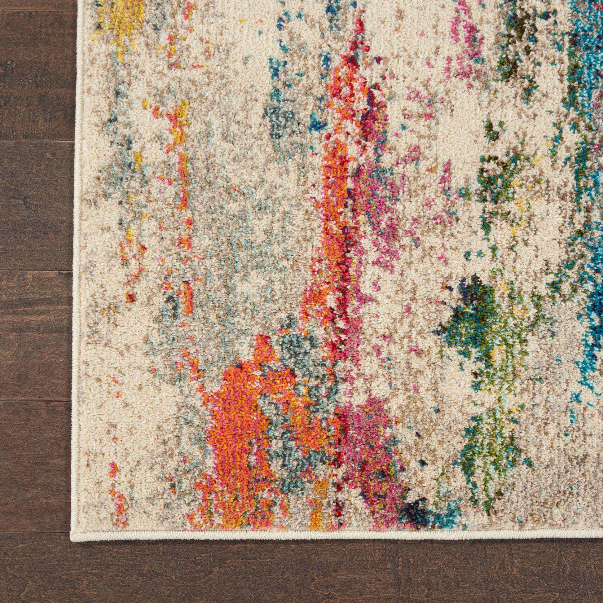 Beige abstract area rug with colorful splashes in orange, pink, blue, green on cream background, on dark wood floor.