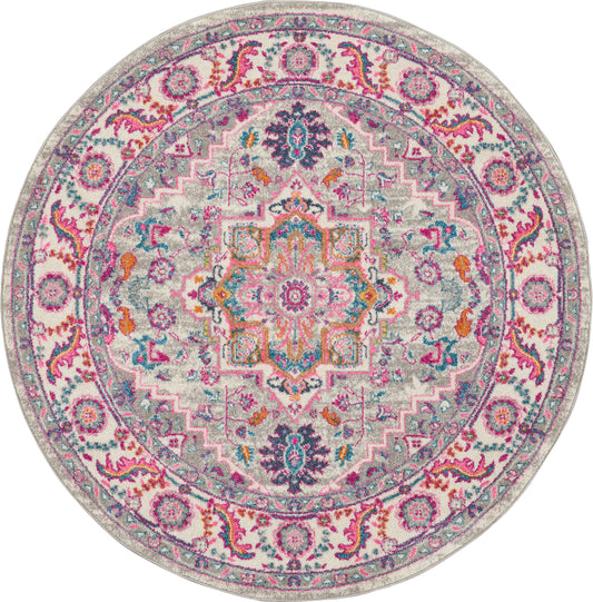 Round multicolor rug with ornate mandala medallion, pink, teal, orange and purple on a gray background.