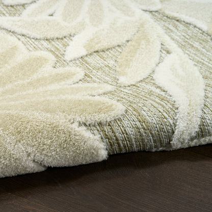 Cream outdoor rug with a leaf motif layered over a textured woven base on dark wood floor.
