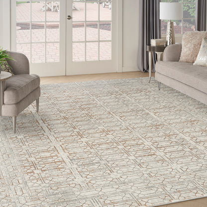 Neutral geometric area rug in cream & tan, in a modern living room with beige sofa, ottoman, & glass doors.