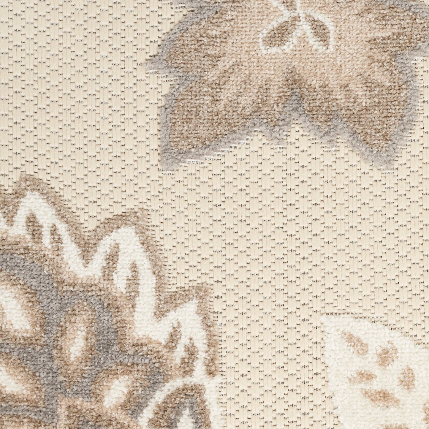 Beige woven rug with a large taupe and cream floral motif and textured weave.