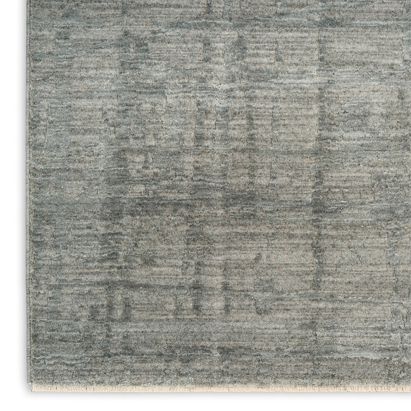 Grey distressed area rug with subtle tonal pattern, low-pile texture and beige fringe, rustic-modern living room decor.