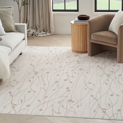 Cream rug with light tan vine pattern in living room, paired with white sofa, taupe armchair, and round wooden side table.