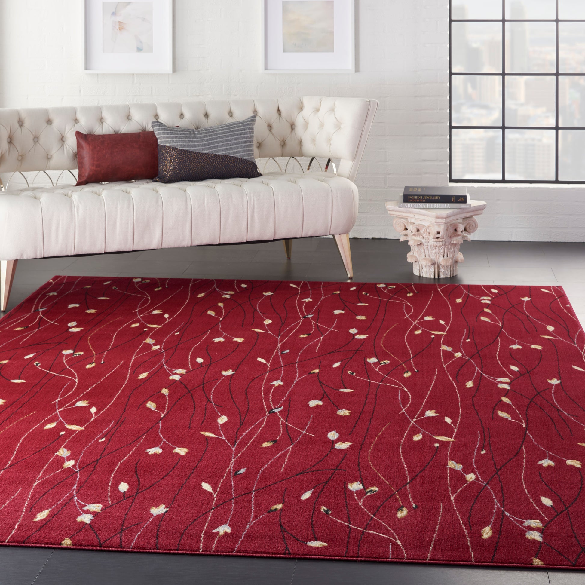 Crimson 8' x 10' area rug with white and pale yellow vine pattern in a modern living room; cream tufted sofa and side table visible.