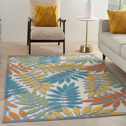 Colorful tropical leaf-pattern area rug in blue, teal, yellow and orange; modern living room with grey furniture.