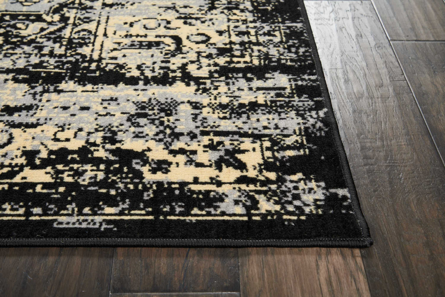 Rectangular distressed rug (8' x 10') in black, cream, and gray on dark wood floor; abstract vintage pattern with a black border.