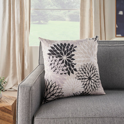 Square throw pillow with tropical black and white print on a gray sofa.