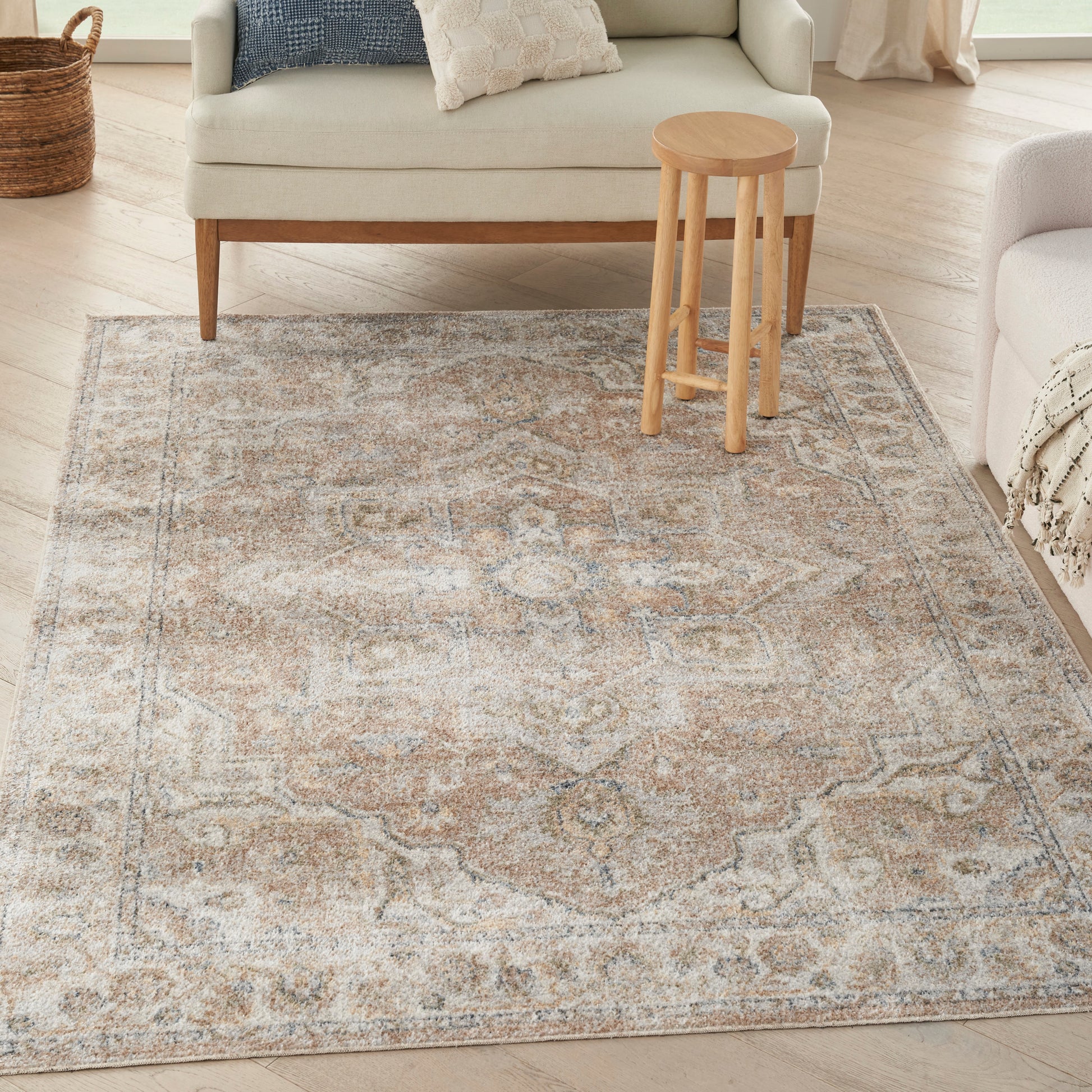 Rectangular oriental area rug in beige, brown and blue-gray on light wood floor beside a beige sofa and wooden stool.