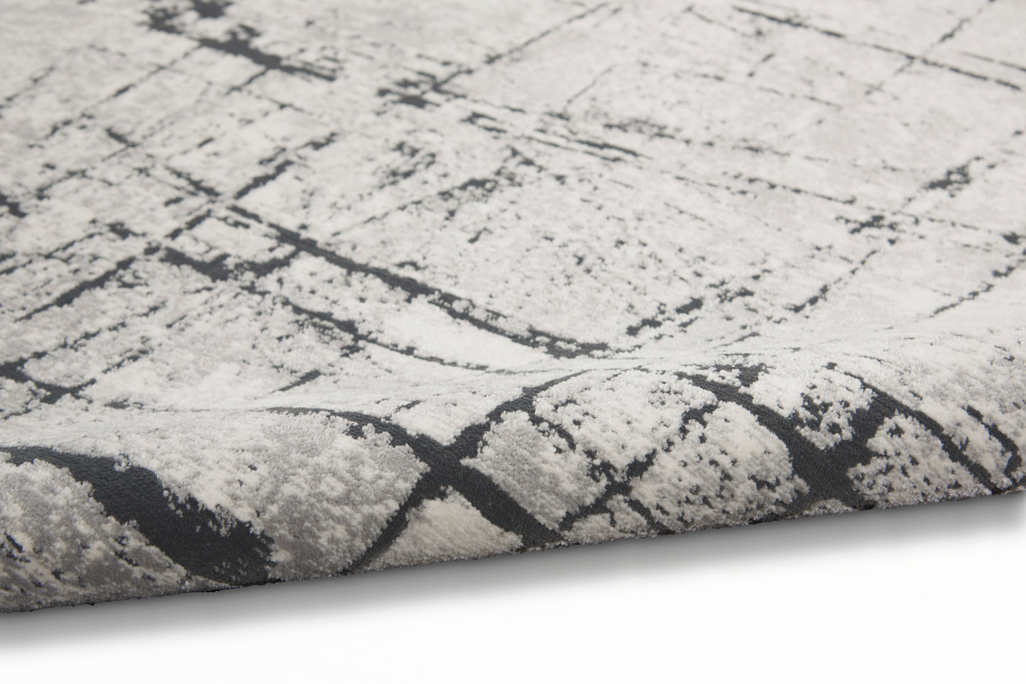 Close-up of a light gray rug with a dark charcoal crackle abstract pattern and plush pile.