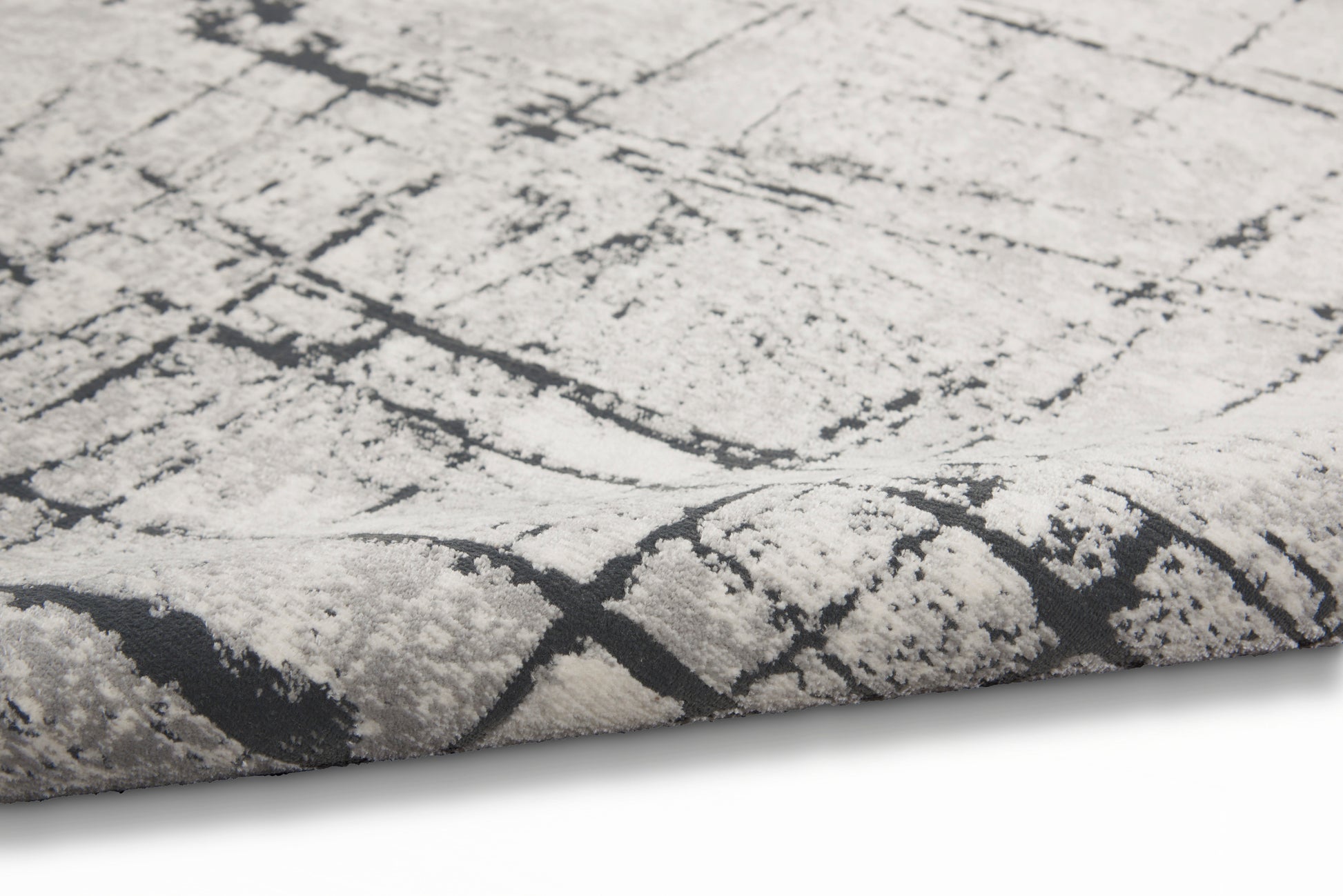 Close-up of a light gray rug with a dark charcoal crackle abstract pattern and plush pile.