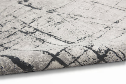 Close-up of a light gray rug with a dark charcoal crackle abstract pattern and plush pile.