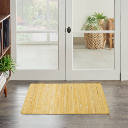 Yellow woven entry rug in front of white glass-paned French doors; modern foyer with plants and dark wood floor.