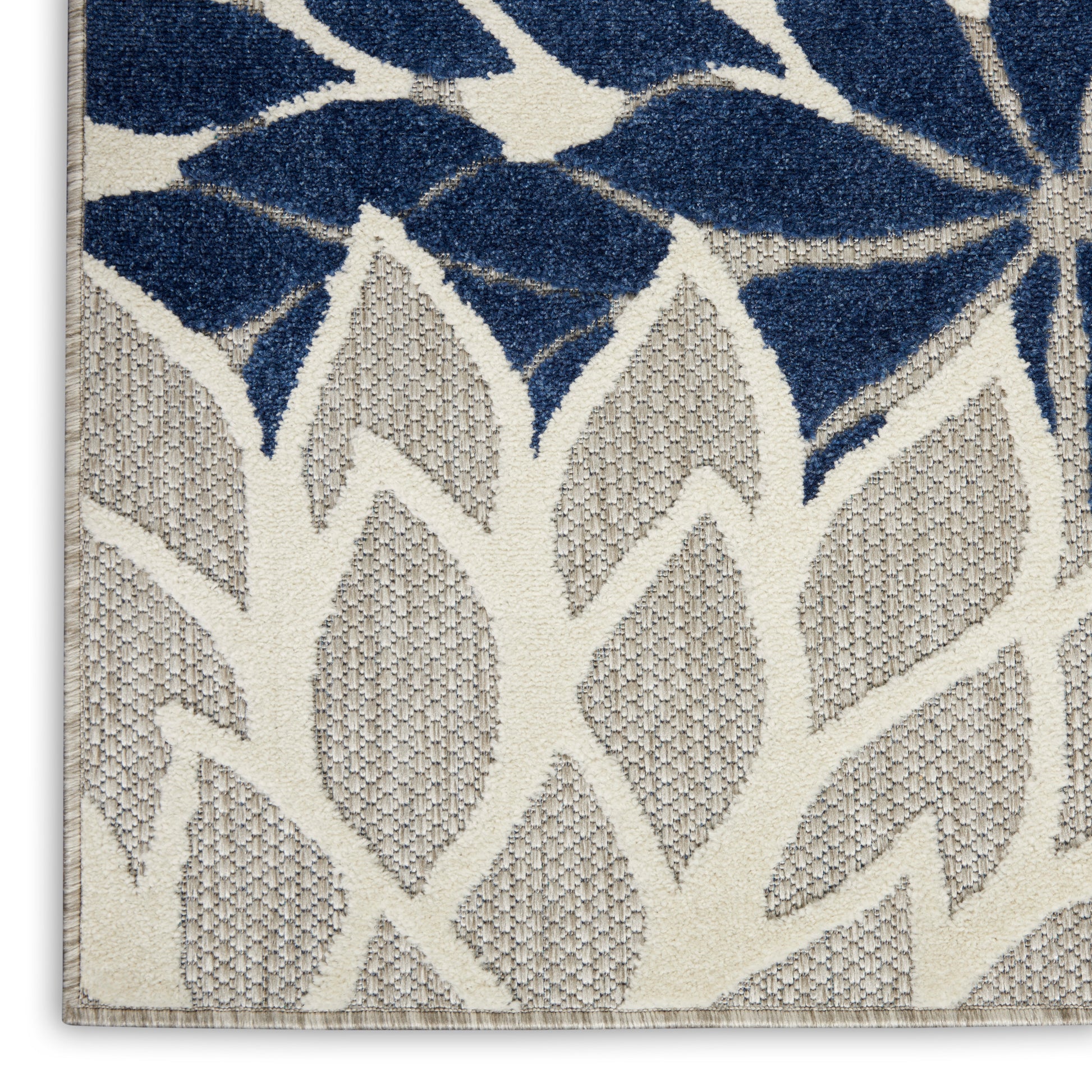 Two-tone botanical area rug with navy blue and beige leaf motifs; woven texture and beige border.