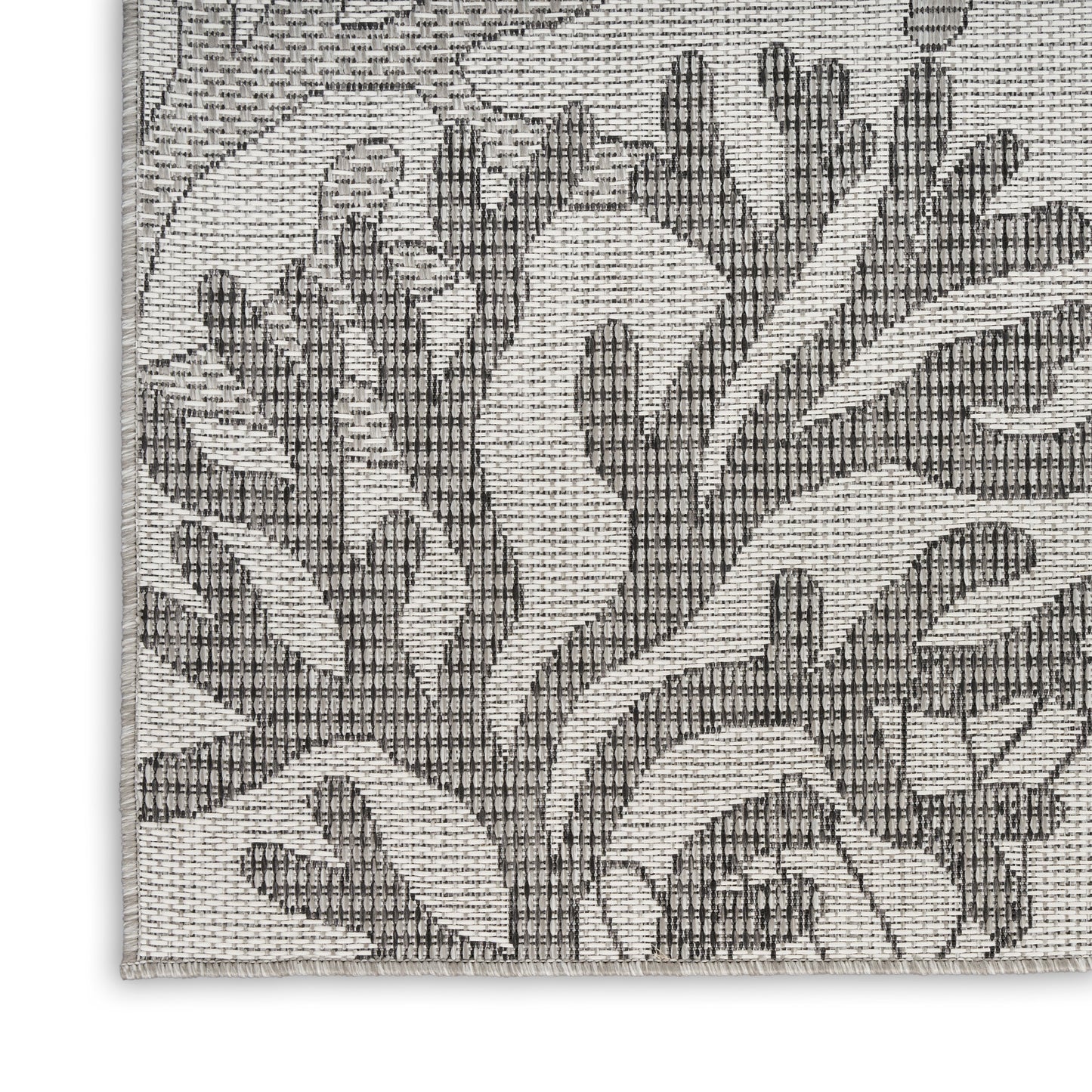 Gray and cream woven rug corner with coastal nautical motif and textured jacquard weave.