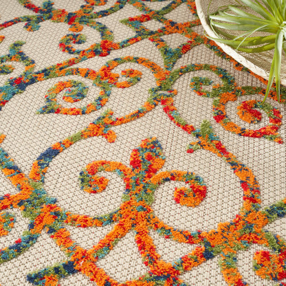 Beige area rug with vibrant orange, teal, blue and red scrolling pattern; woven textured surface.