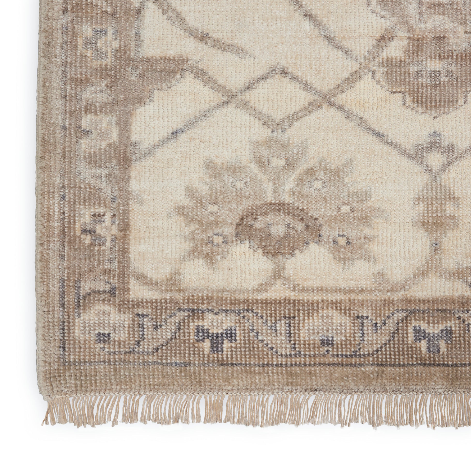 Beige oriental rug with brown floral border and fringe along edge.