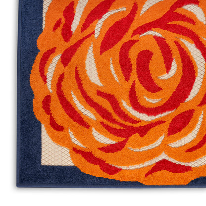 Close-up of a woven rug with a bold orange floral motif on ivory field and navy border.