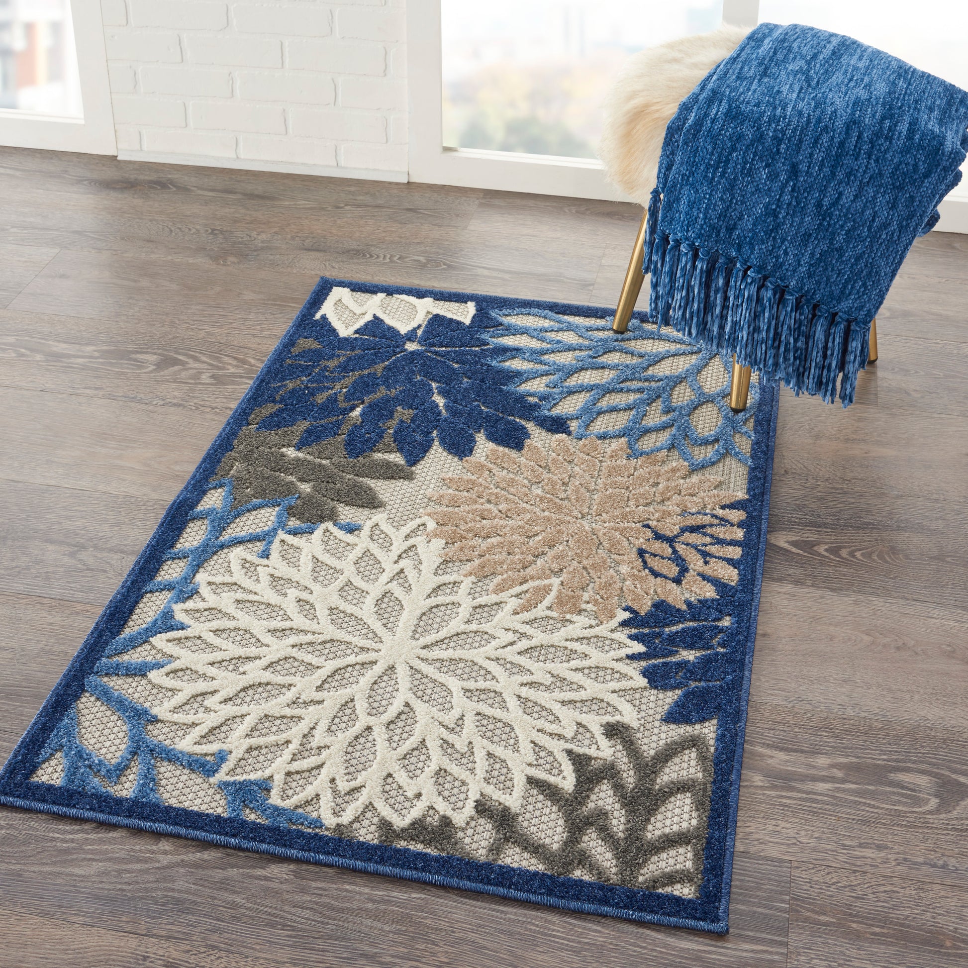Blue area rug with white and beige floral mandala patterns and a dark border on a wood floor.