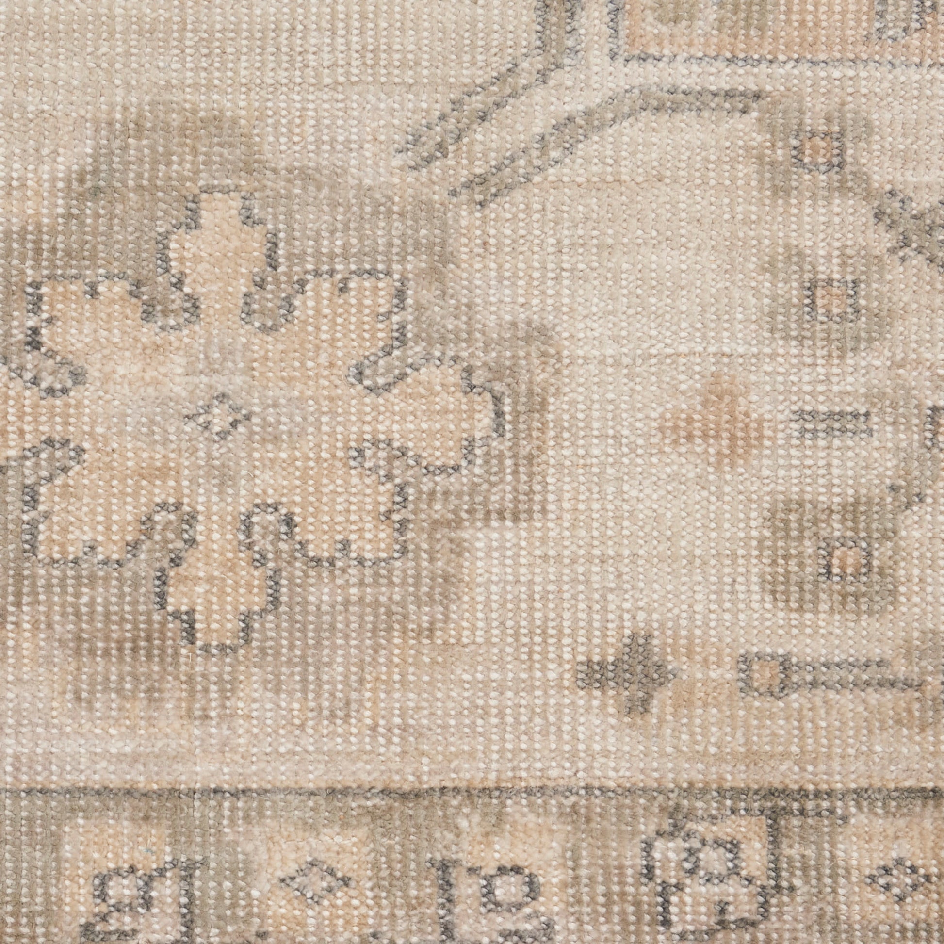 Beige vintage-style woven rug with faded cream floral medallion pattern and subtle border