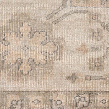 Beige vintage-style woven rug with faded cream floral medallion pattern and subtle border