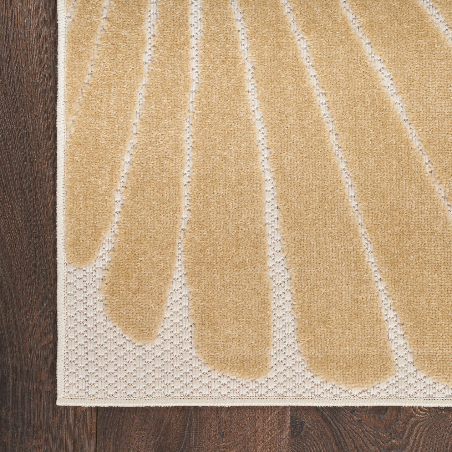 Beige woven outdoor rug with tan teardrop shapes and white border, laid on an outdoor surface; modern, casual style.