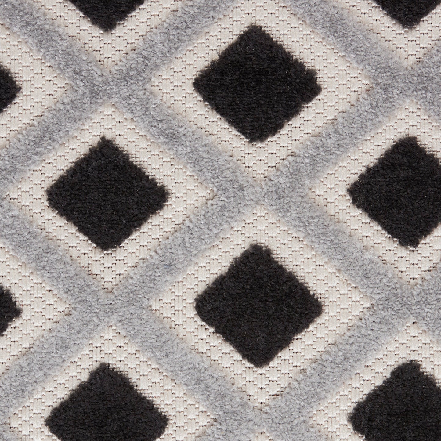 Plush rug featuring interlocking diamonds: black diamonds framed by light gray diamonds on a cream ivory background.