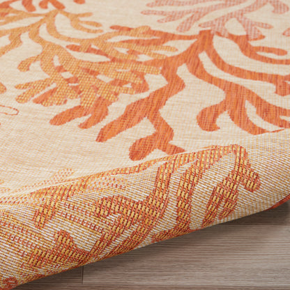 Cream and orange woven rug with leaf motif, rolled corner showing textured border, ideal for living room decor.