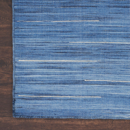 Blue woven area rug with light white horizontal stripes on a dark wooden floor.