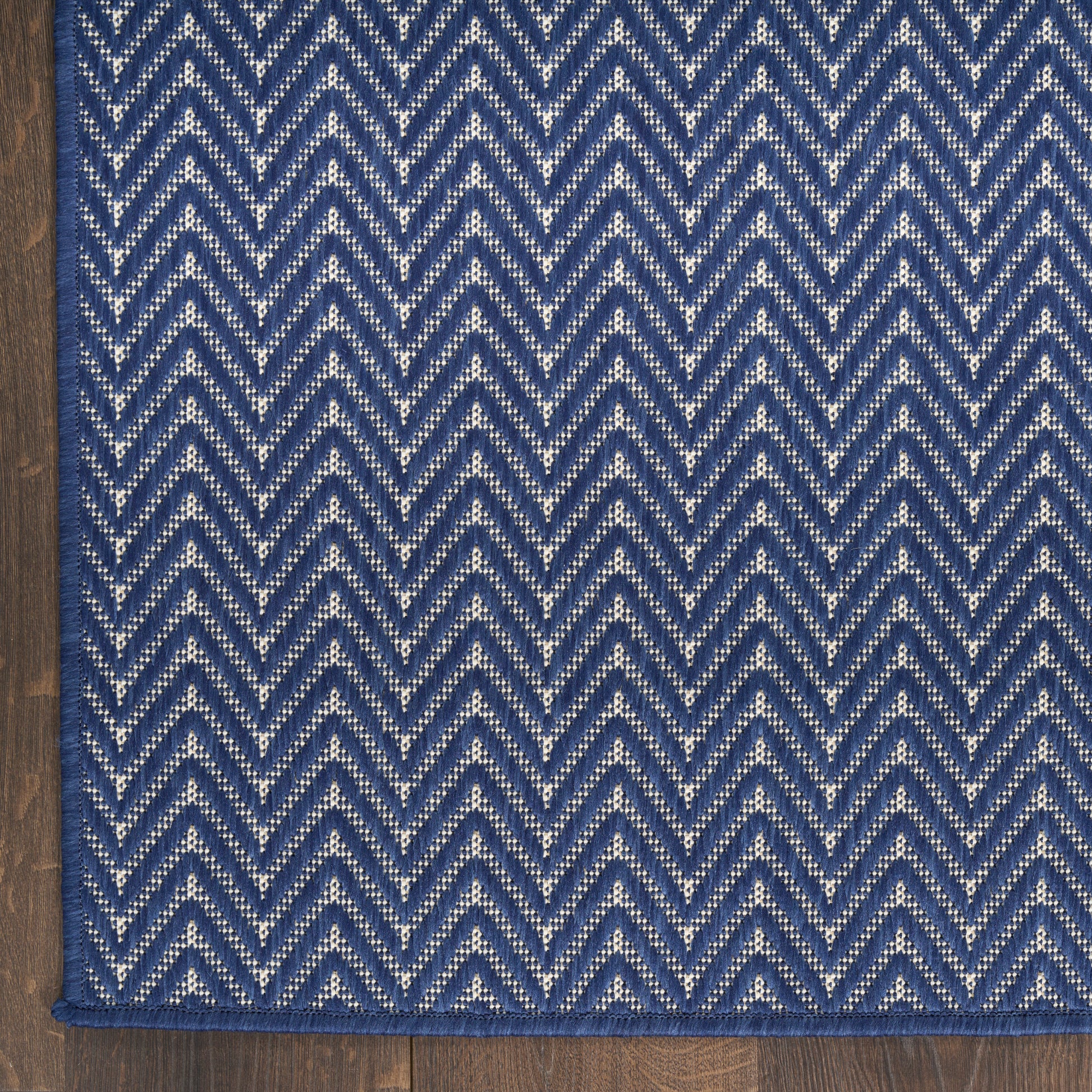 Blue and white chevron woven rug with indigo border on a wooden floor.