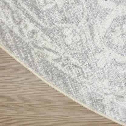 Soft gray and ivory patterned rug with beige edge binding on light wood floor.