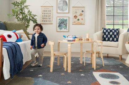 Blue starry kids' rug in a cozy playroom with framed wall art.
